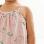 Child wearing a pink dress with colorful patterns on a white background
