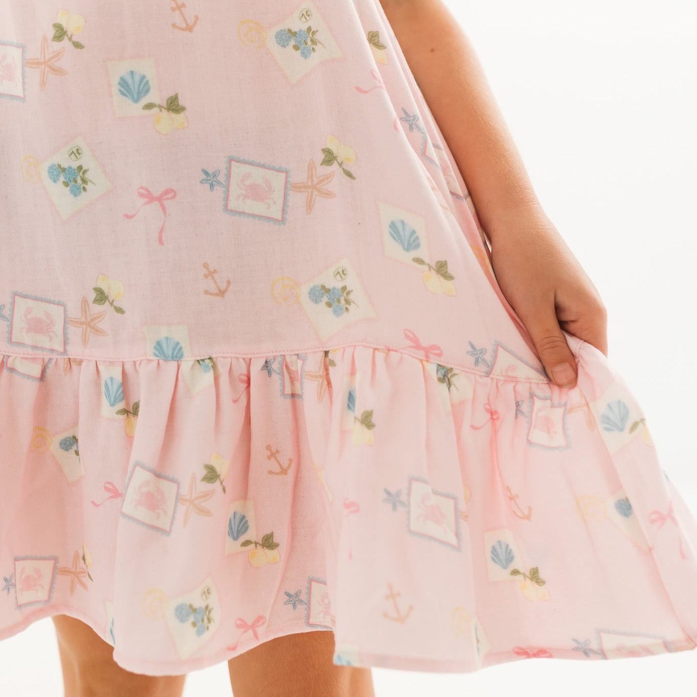 Pink dress with floral, bow and shell pattern on a white background