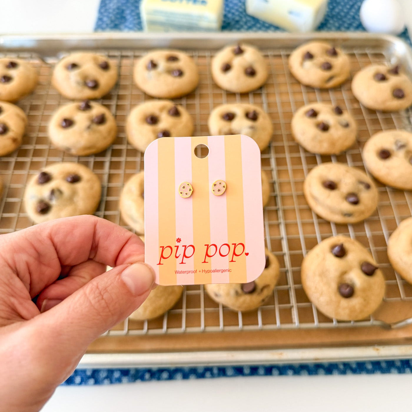 Hand holding a 'pip pop' card in front of a tray of cookies with chocolate chips.