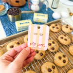Hand holding a 'pip pop' product card with cookies and baking ingredients in the background