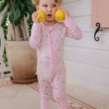 Child in pink pajamas holding lemons outdoors