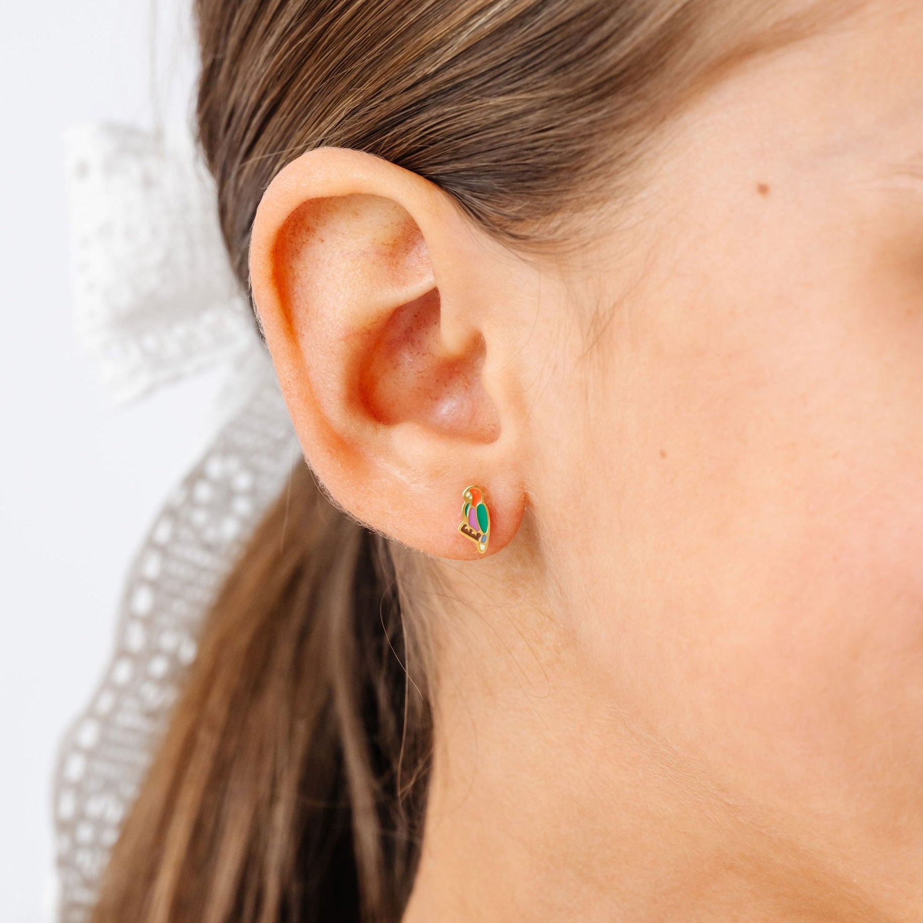 close-up of a girl wearing a colorful parrot earring stud