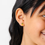 Close-up of a girl wearing a pineapple-shaped earring with a white background