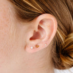 Close-up of an ear with pearl, bow and diamond stud earrings.