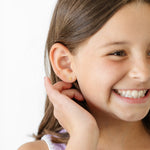 Young girl wearing a gold  number 5 earring on a white background