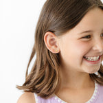 Young girl with a smile and gold number. 4 earrings on a white background