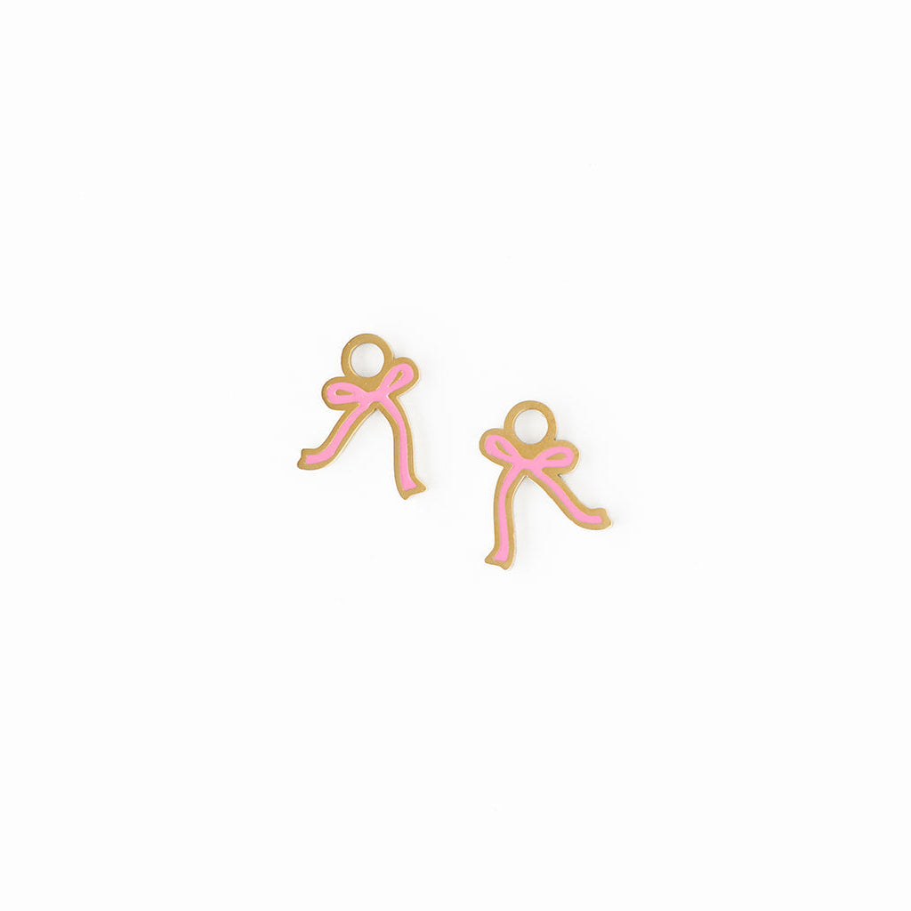 Pair of pink bow-shaped charm earrings on a white background