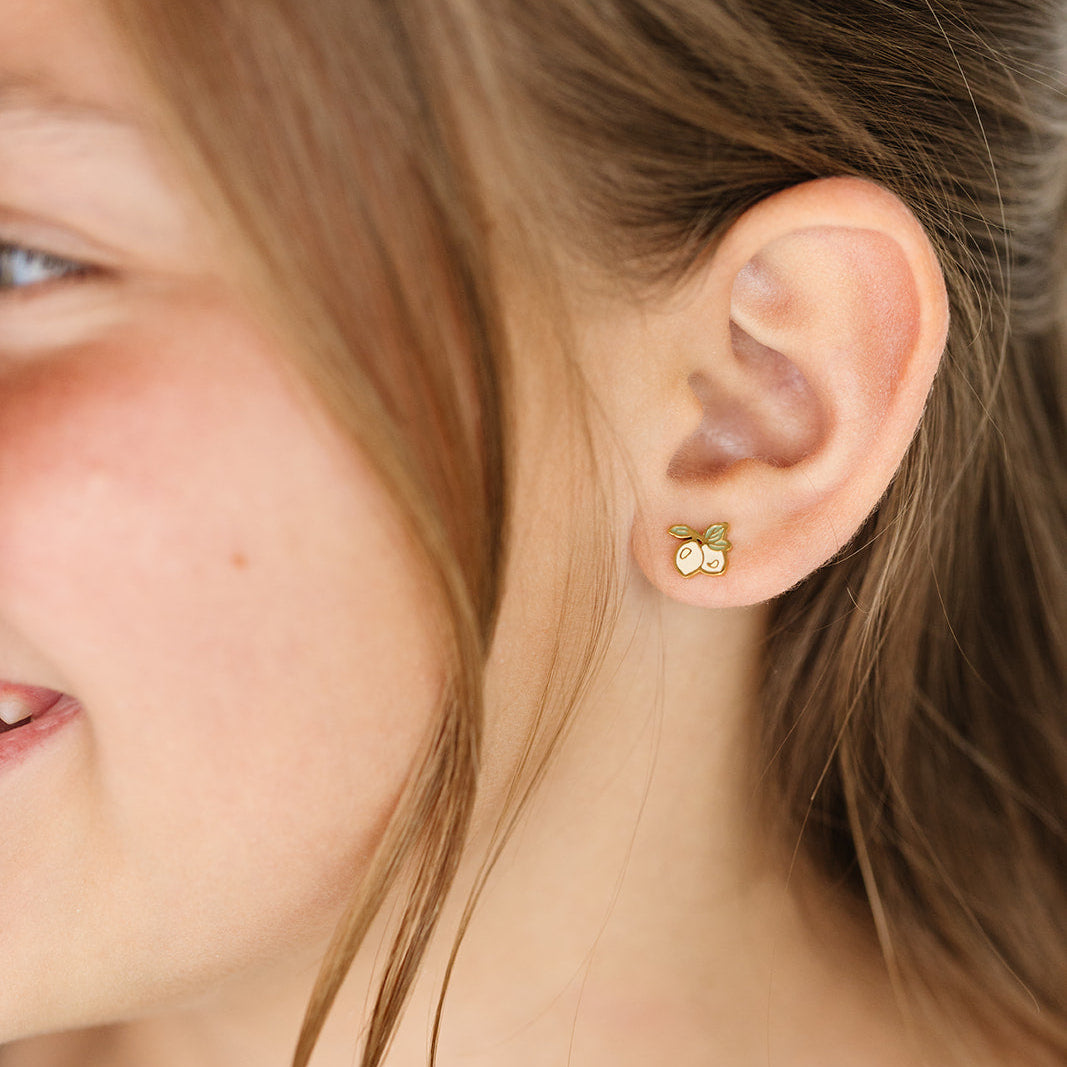 girl wearing a gold and yellow lemon stud earrings