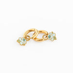Gold charm with floral designs on a white background