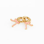 Gold hoop earrings with pink bow charm on a white background