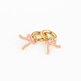 Gold hoop earrings with pink bow charm on a white background