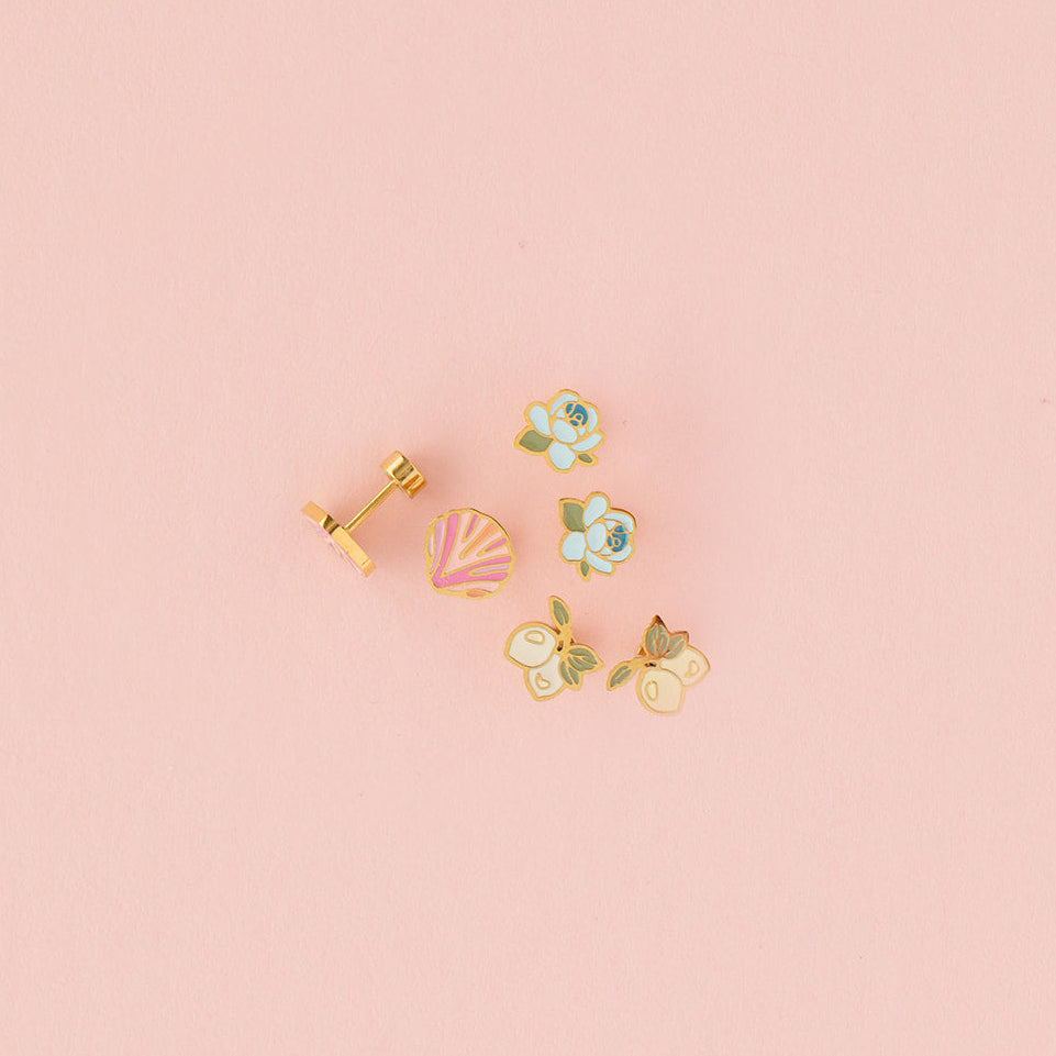 Set of small earrings on a pink background