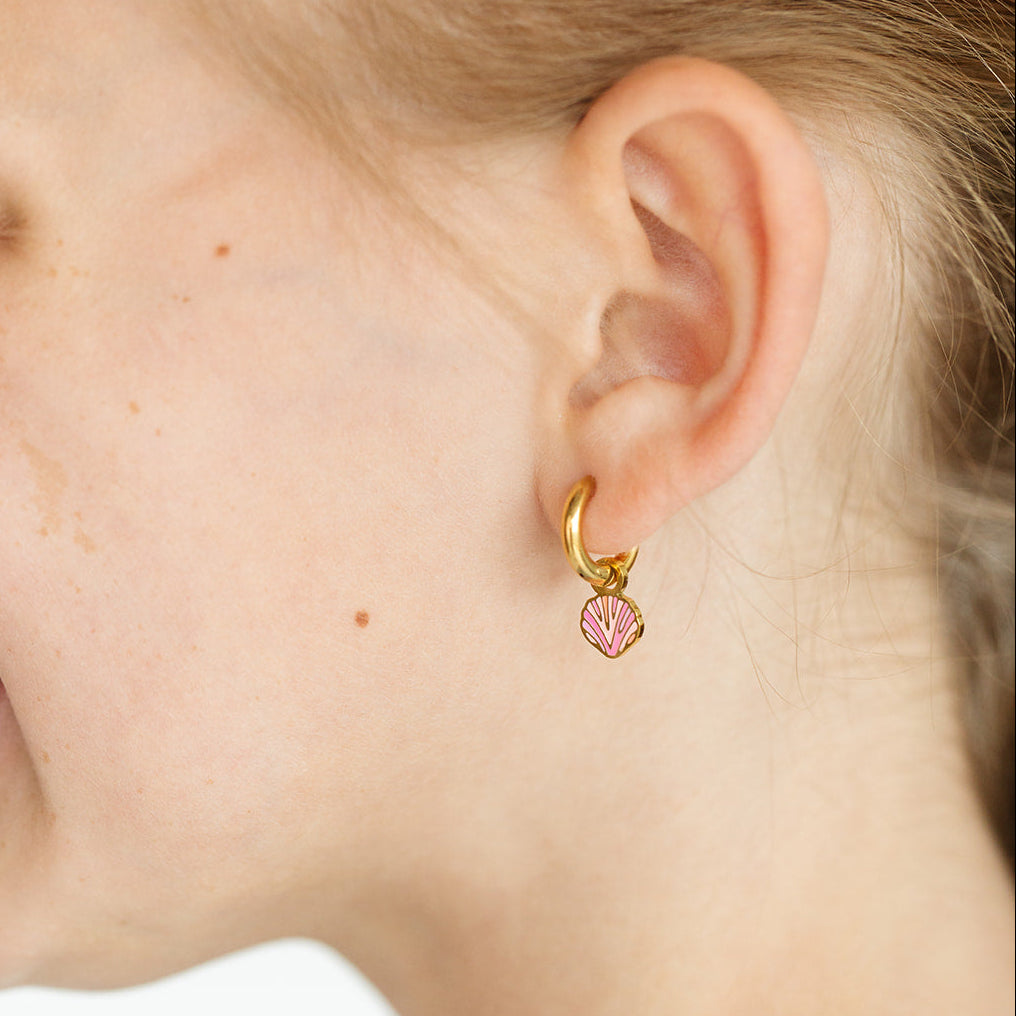 Girl wearing a gold hoop with pink seashell charm