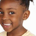 Young girl with a smile wearing a butter stud earring on a white background