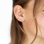 Close-up of a girl wearing a gold whisk earring